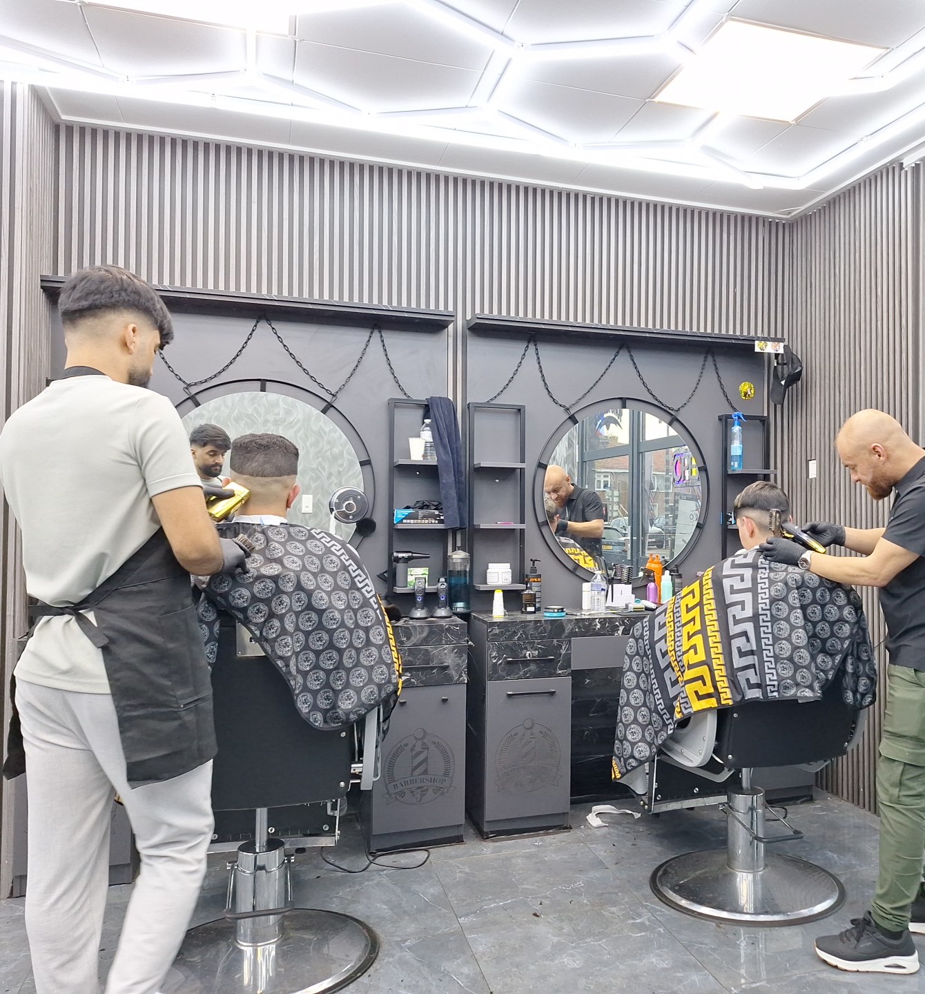 Twee barbers aan het werk bij de stoelen met ronde spiegels
