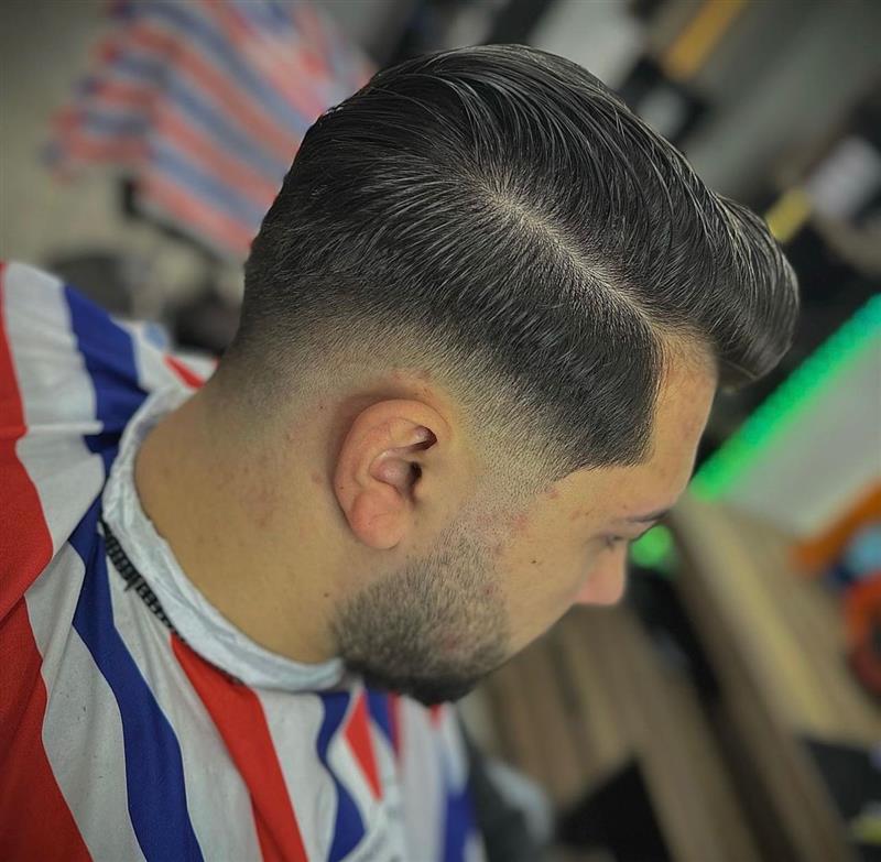 Een strakke fade met zijscheiding, net geknipt bij Barber IKO