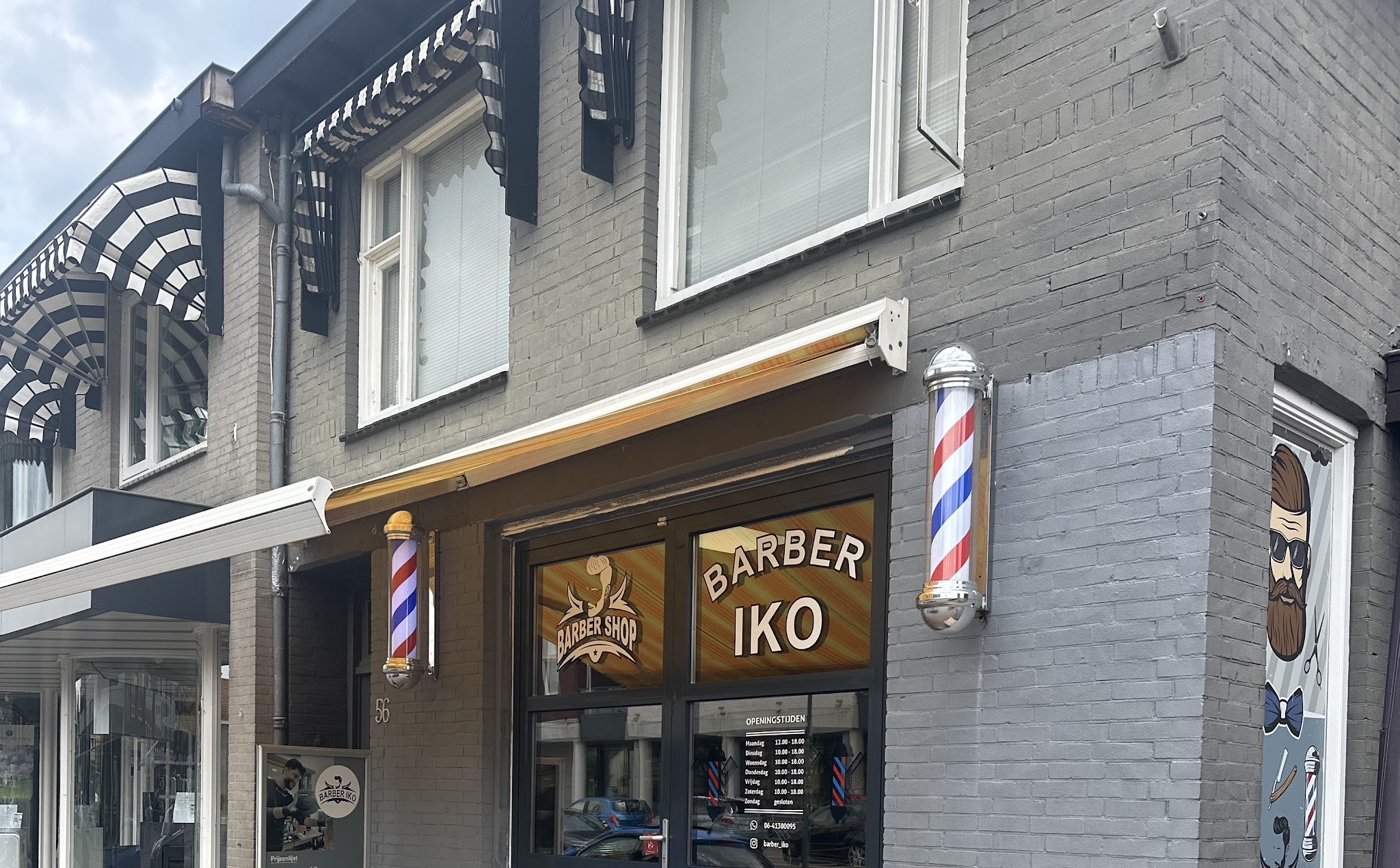 De gevel van Barber IKO aan de Dorpsstraat 56 met de barberpalen en de belettering op het raam